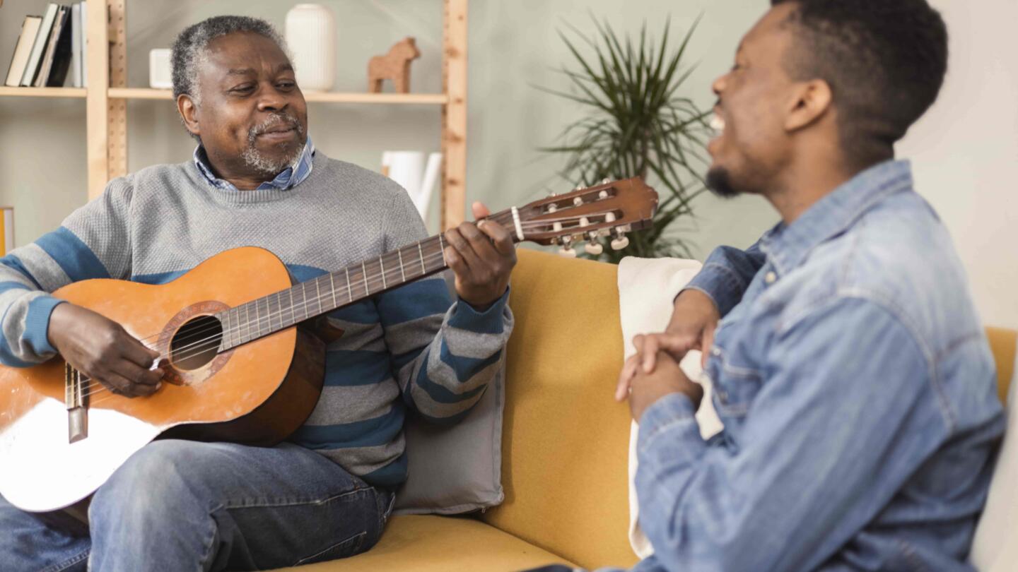 Old man and young man playing guitar